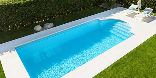 A freshly cleaned swimming pool with a well maintained green lawn.