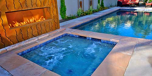 A custom swimming pool with a fire fit and a hot tub