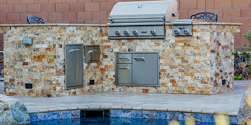 A barbecue grill kitchen setup next to a pool