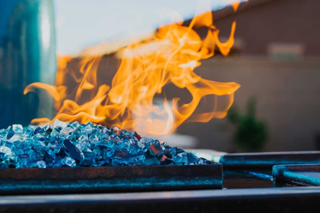 A close up a pool fire feature with blue glass fragments built by our Tucson pool builders