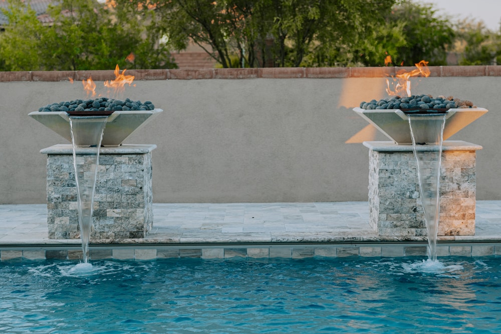 Twin fire pillars pouring water into a custom luxury pool in Tucson