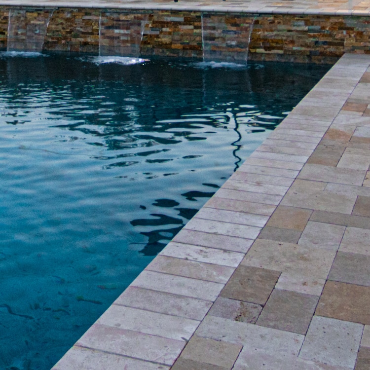 The stone tile deck of one our modern pools