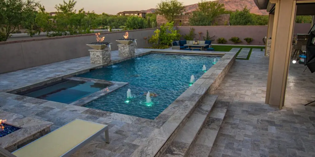 custom pool in a backyard with fountains and fire