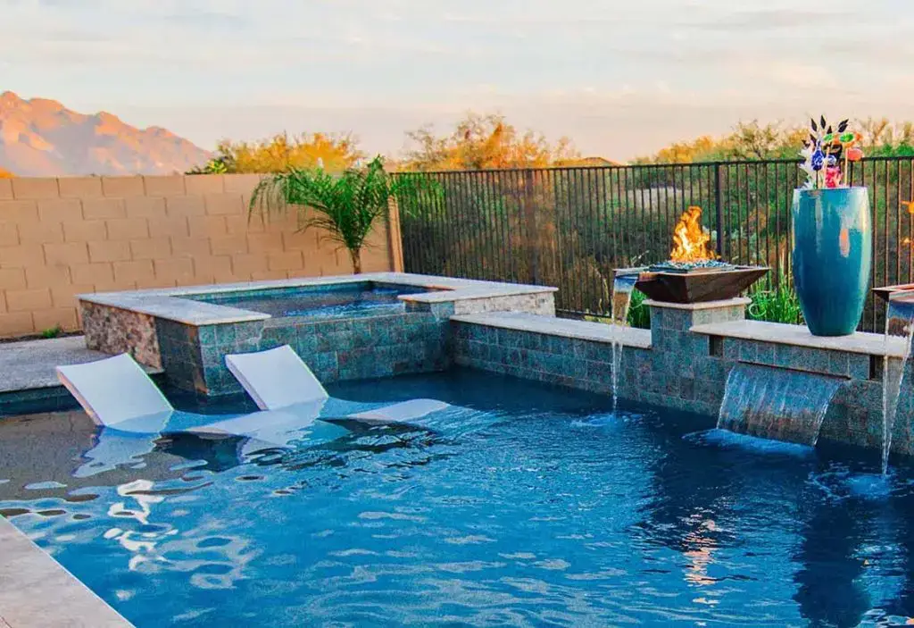 a resort style custom pool with a spa and spillover fountains built by pools by design