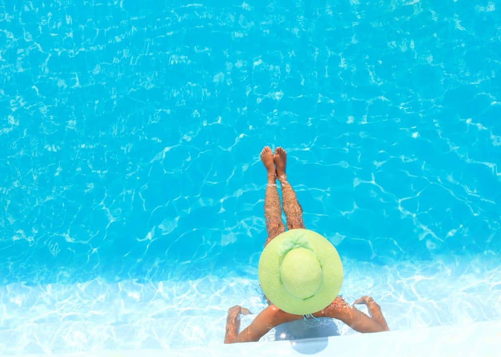 a women in a beach hat sitting in a pool
