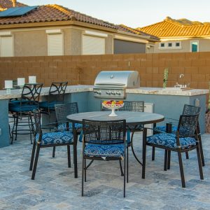 An outdoor living space with a grill island and seating area