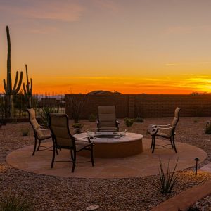 A fire pit and outdoor living area with a Tucson sunset in the background