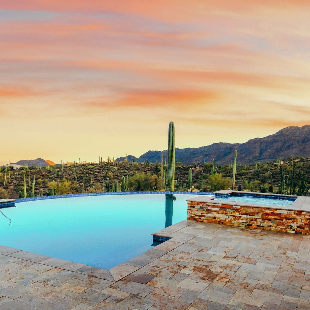 An infinity pool overlooking a gorgeous sunset with a spillover spa 