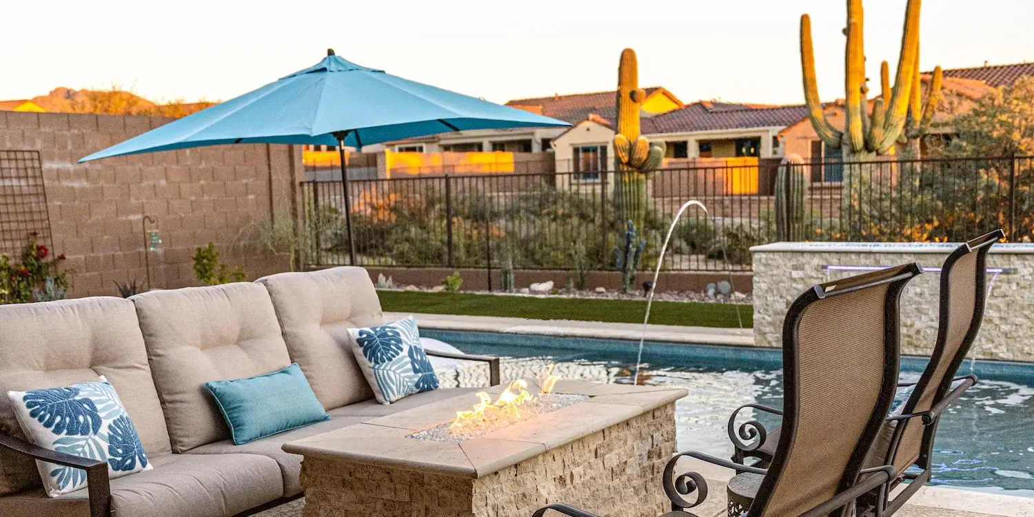 outdoor pool with sofa and chair near firepit designed by pools by design