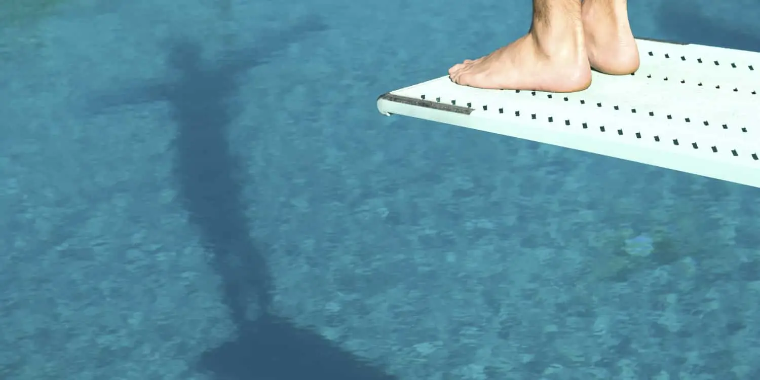 a person about to dive off a boarding board in a pool designed by pools by design