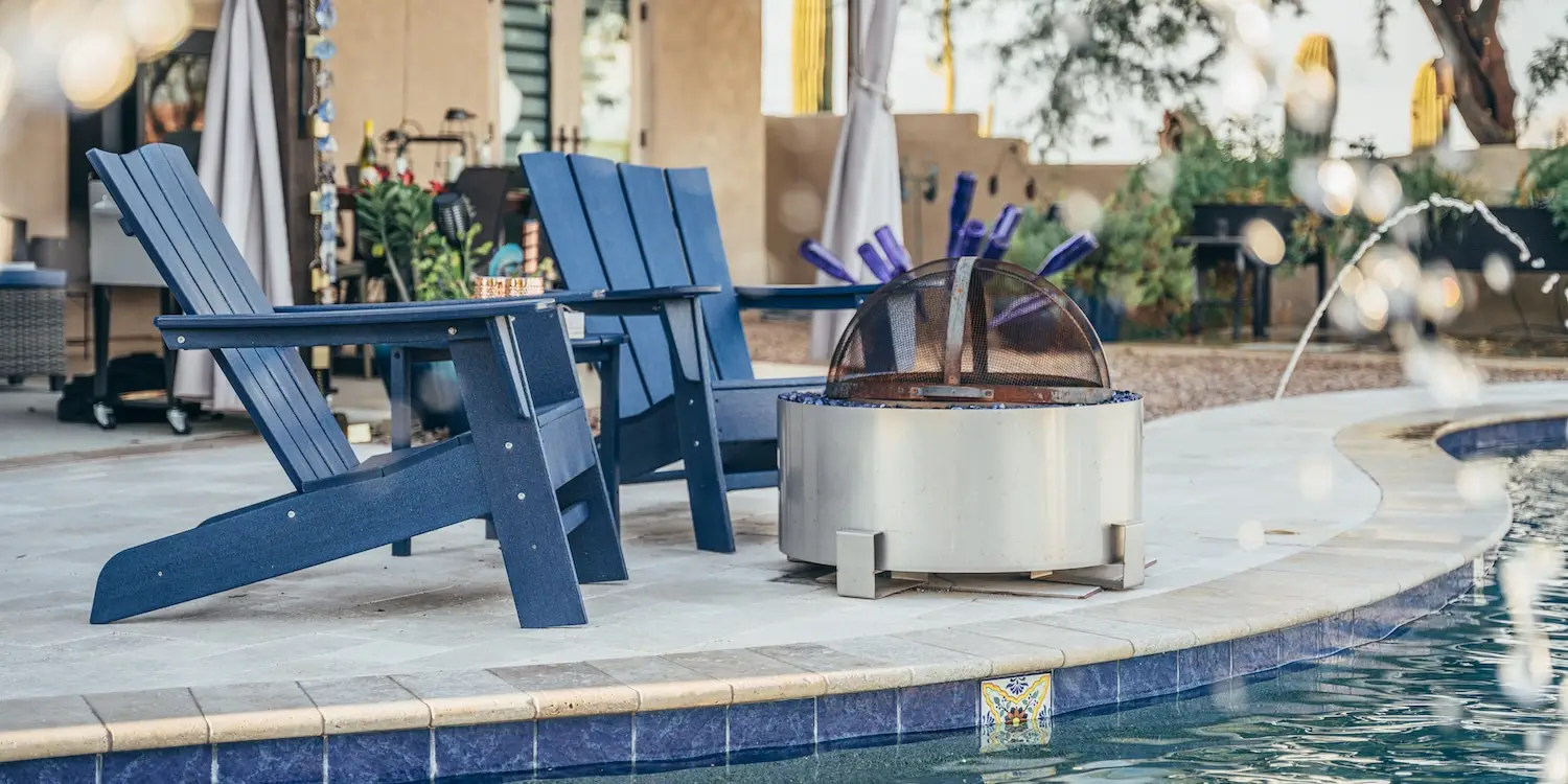 chairs and poolside decor next to a pools by design pool